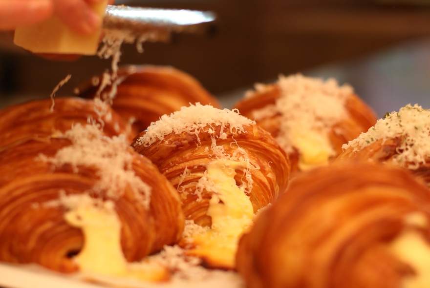 Cheese-filled croissants with parmesan cheese being grated over the top.