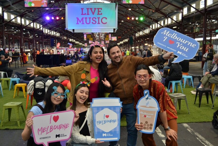 A bunch of young people holding signs that say 'I love Melbourne' at the Queen Victoria Market.