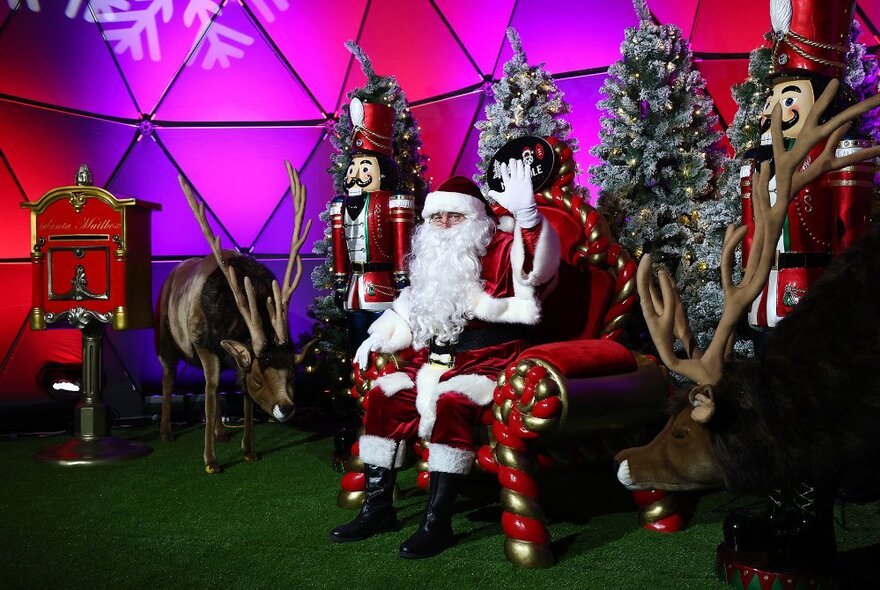 Santa waving from inside a pink dome.