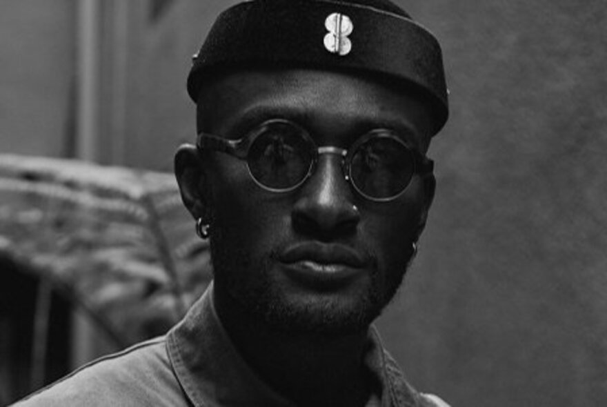 American saxophonist and composer Isaiah Collier, wearing dark sunglasses and a beanie, black and white image.