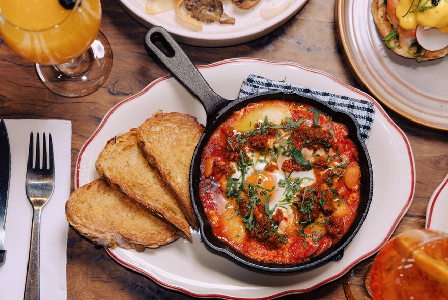 A brunch dish with baked eggs in a cast iron pan and toast.