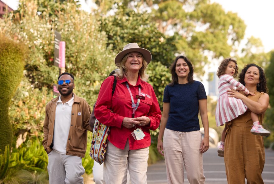 A group of people on a guided walk of the Royal Botanic Gardens, with trees in the background.