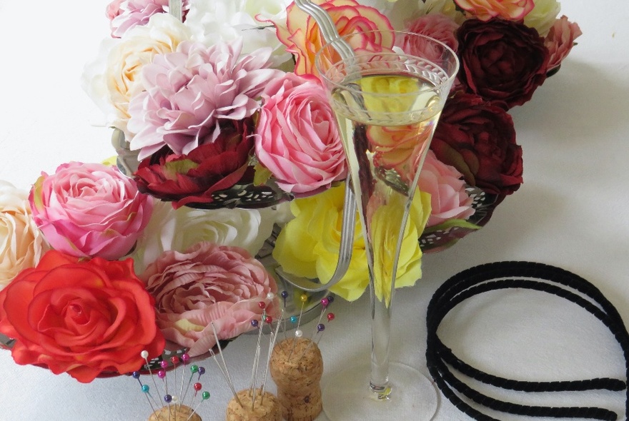 A variety of coloured roses with headbands, coloured pins and a glass of champagne. 