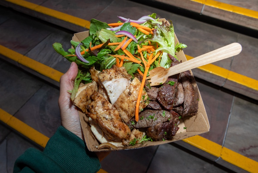 A takeaway meals of meat and salad in a cardboard container.