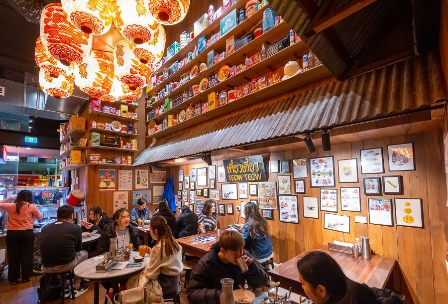 A Thai restaurant with red lanterns hanging from the ceiling and pictures on the wall.