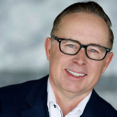 Head-shot of Alan Joyce, a prominent middle-aged businessman, he wears glasses, a white shirt and a dark suit jacket.