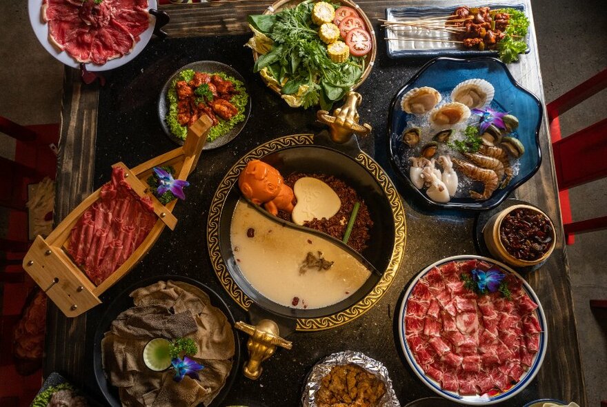 Sichuan hotpot surrounded by ingredients ready to cook. 