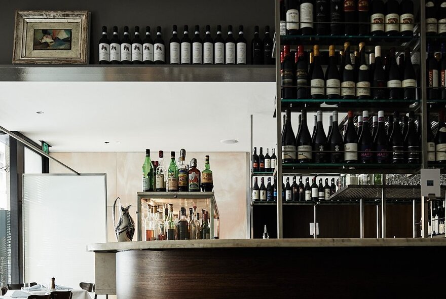 The interior of Il Bacaro restaurant showing the central bar area, with the shelves stocked with bottles of wine and spirits.