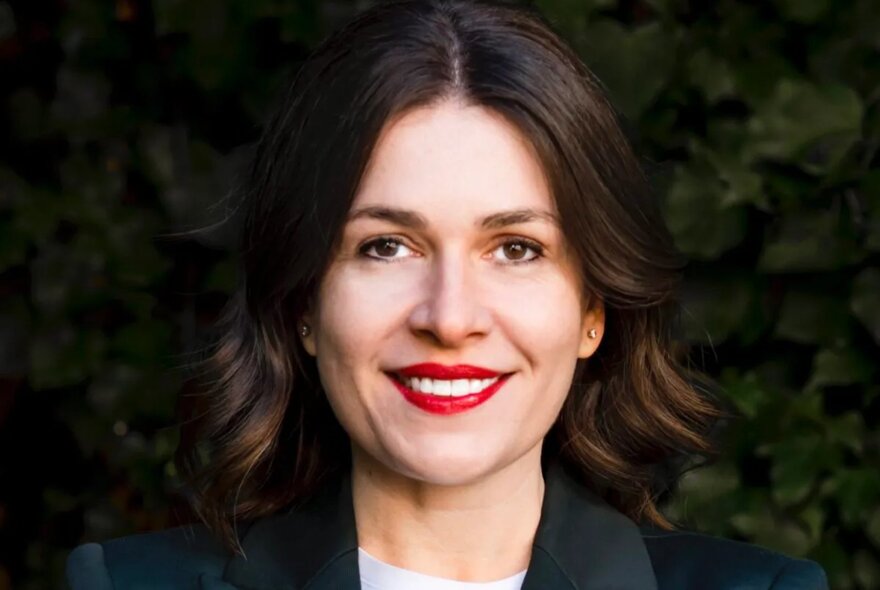 Portrait of a smiling woman with short brown hair and red lipstick.
