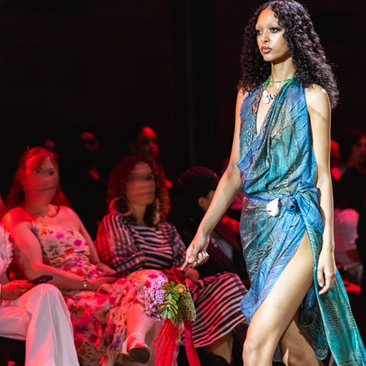 A model is wearing a turquoise outfit and walking down the runway at a fashion show 