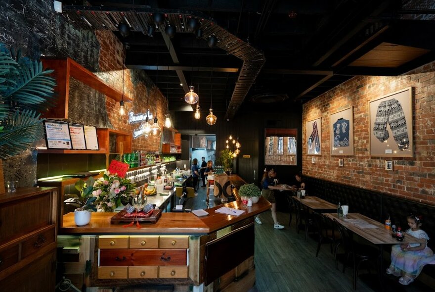 Dimly lit restaurant interior with brick walls and central bar area.