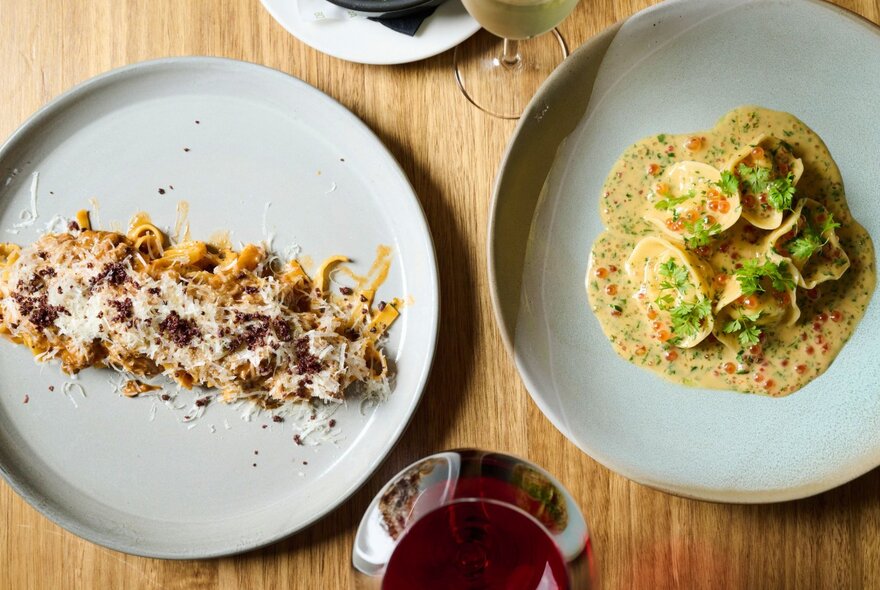 Looking down at two plates of food on a wooden dining table.