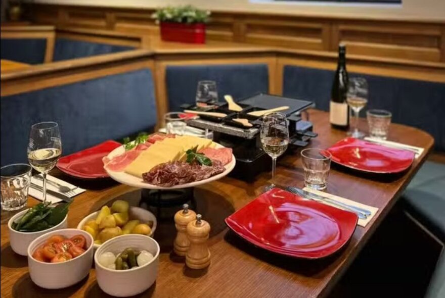 A table set with red square plates and all the ingredients required for fondue. 