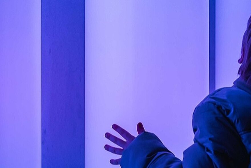 A close-up of a person touching a blue-lit surface.