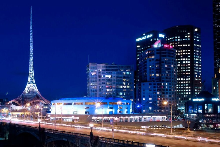 Night image of the Arts Centre Melbourne complex showing the spire, Hamer Hall and other city skyscrapers in the background.