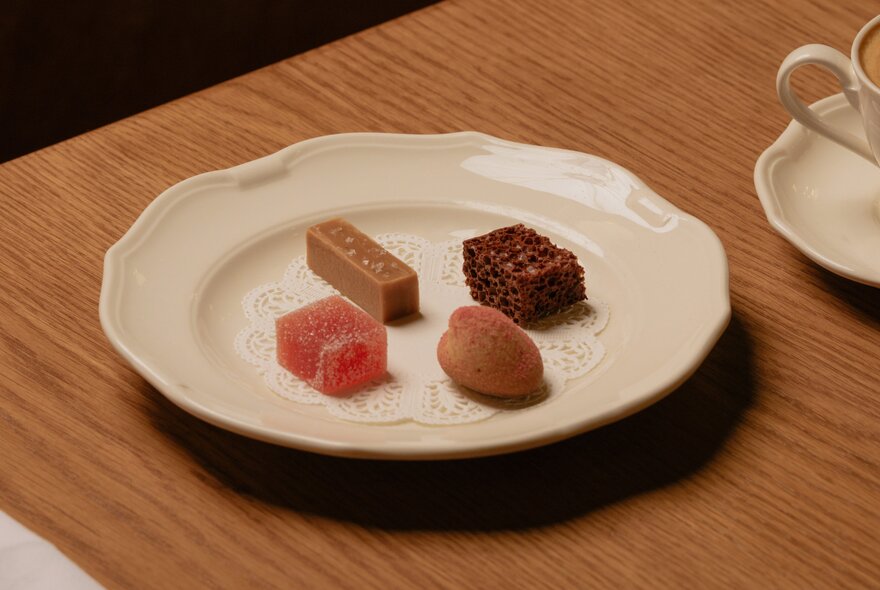 A white plate of small and delicate desserts on a restaurant table.