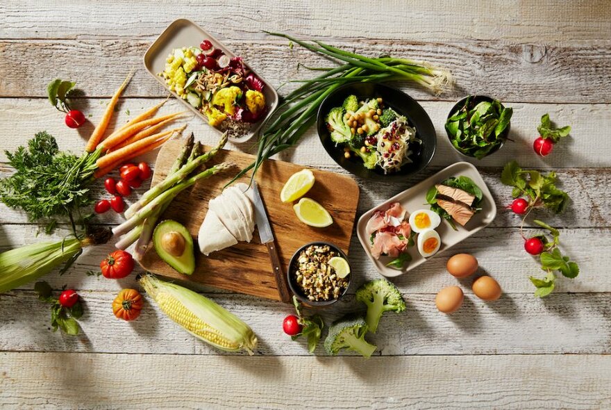 A table covered in fresh salad ingredients and prepared salads