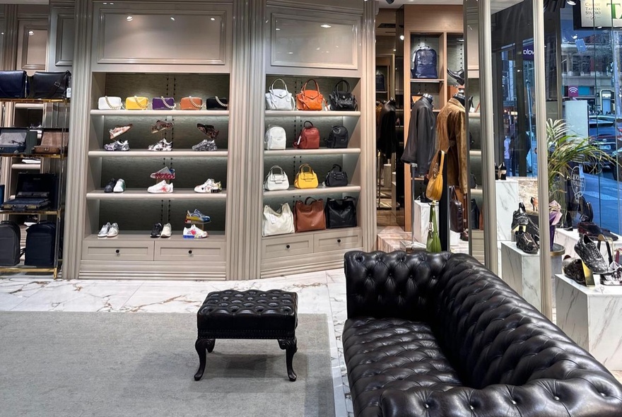 Retail store interior with display shelves of leather goods and chesterfield seating.