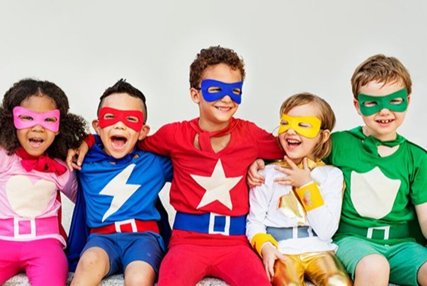 A row of seated kids wearing colourful super-hero costumes with masks.