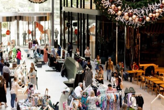 View of a Christmas market at Collins Square from above, with shoppers browsing stalls.