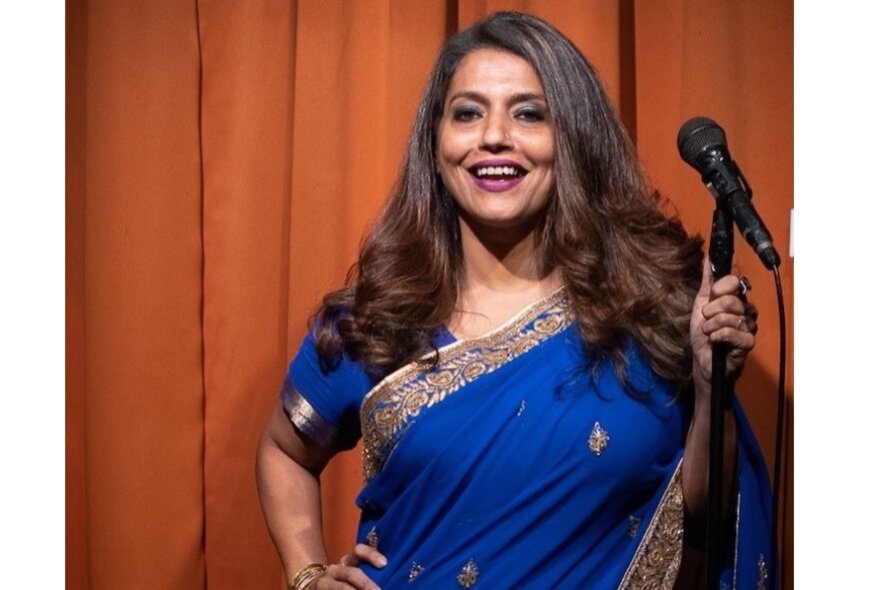 Woman wearing a sari holding a standup microphone.