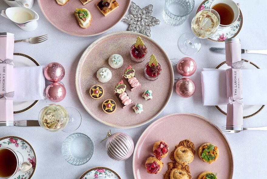 Pink-themed festive afternoon tea with star-shaped cakes on pink plates with pink crackers and baubles.