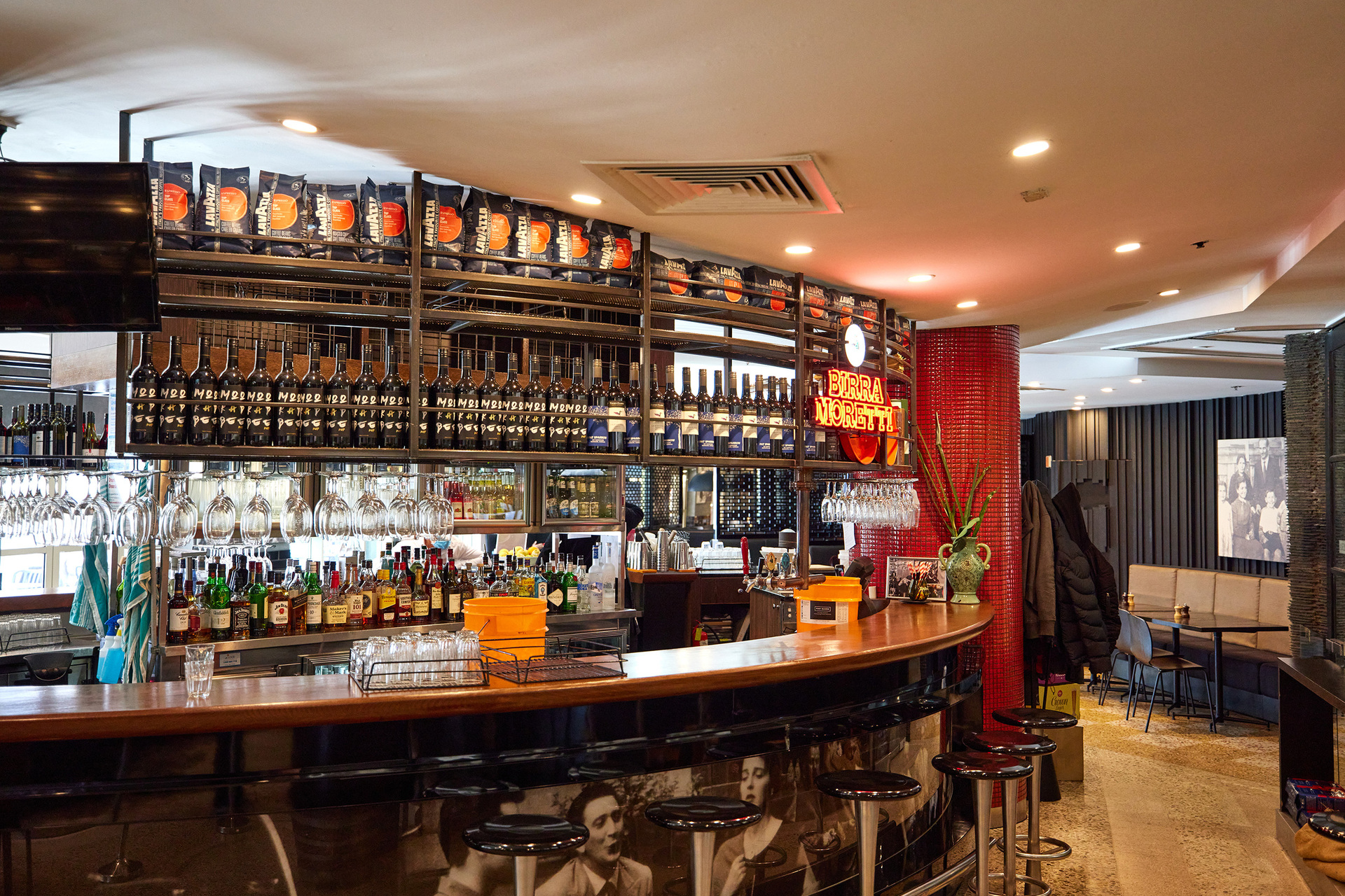 A bar in an Italian restaurant with bottles of liquor and wine lined up on the shelves.