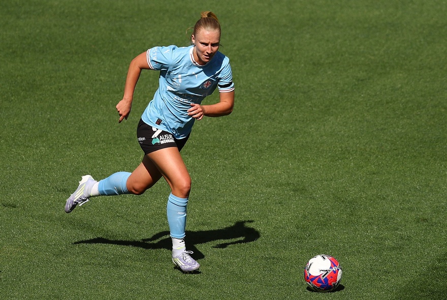Woman soccer player kicking a ball during a game.