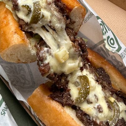 Cheese and beef sandwich in wrapper.