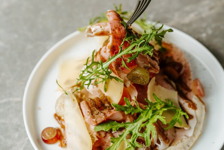 Close up of a restaurant dish piled hight with garnishes.