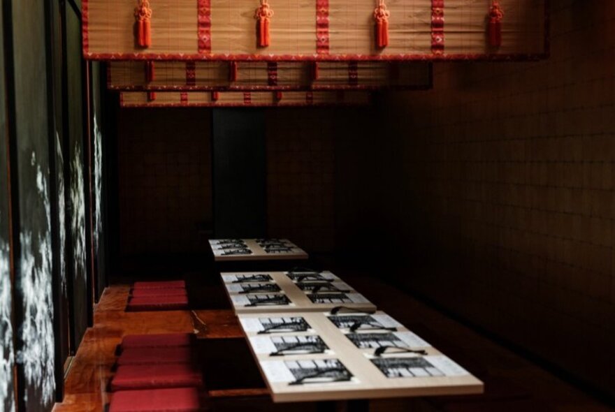 The minimalist interior of a Japanese restaurant with traditional Japanese-style seating and bamboo screens.