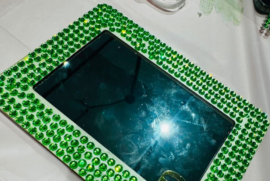 Jewelled mirror framed with green gems.
