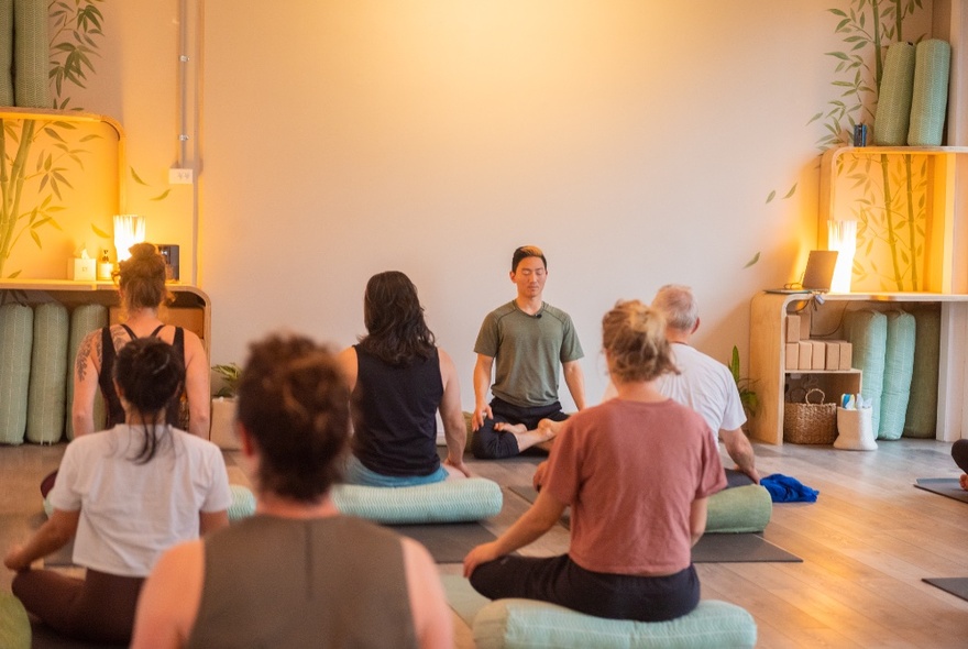 People attending a yoga class on mats in a room with soft lighting.