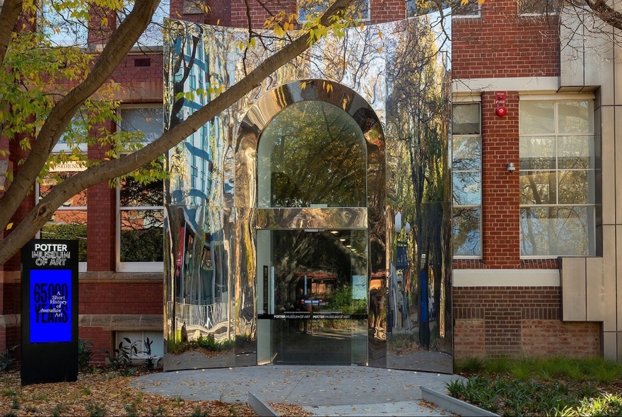 The exterior of the Potter Museum of Art, showing large arched doorway, a footpath and a tree out the front.