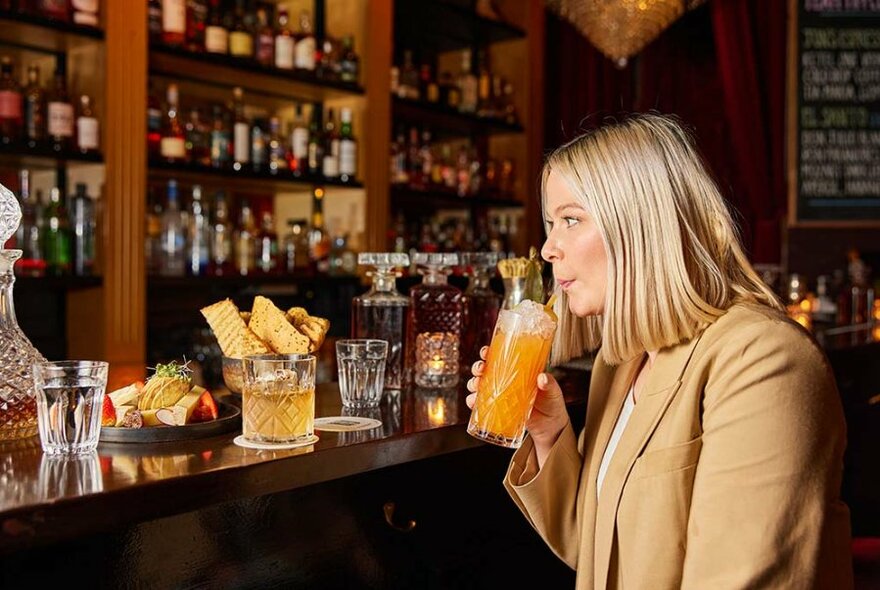 Person sipping a drink at a bar.