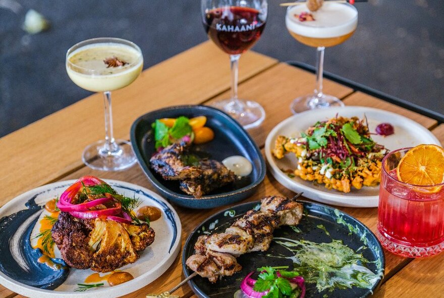 A table set with colourful Indian dishes and cocktails. 