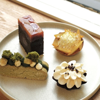 Four small, decorative Japanese pastries on a beige plate. 