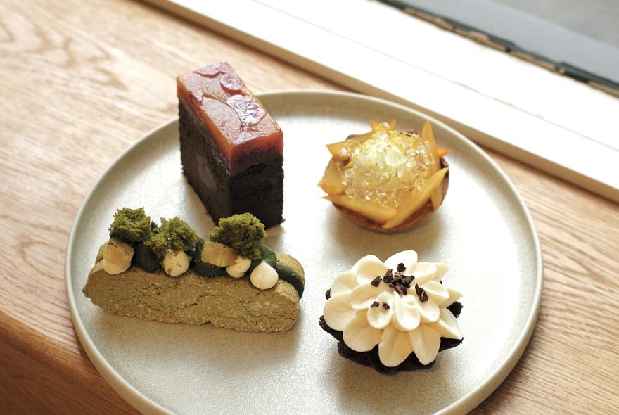 Four small, decorative Japanese pastries on a beige plate. 