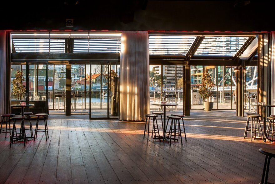 Cargo sheds interior with old wooden floors, open doors and bar stools.