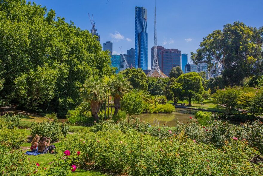 Two people picnicking in a lush city garden overlooking the city. 