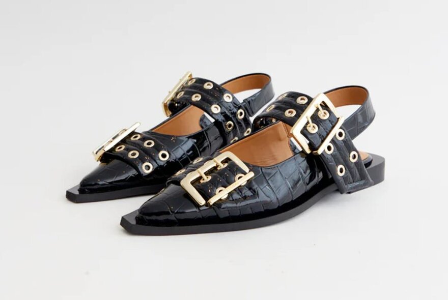 Ganni croc-embossed black leather ballet slides with large gold buckle straps.