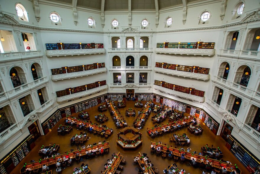 An aerial shot of desks arranged in a sunburst shape in a grand library.