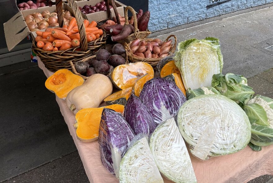 A display of vegetables for sale including quartered cabbages and halved butternut pumpkins.