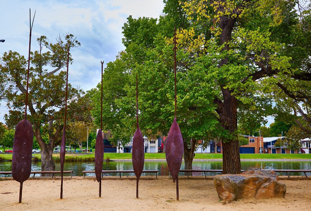 An art installation featuring 5 large metal shields next to the river.