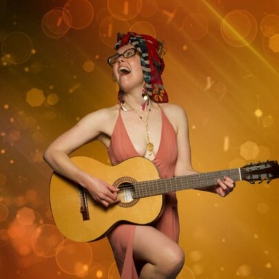 Musician with guitar playing against abstract golden background, mouth open and leg raised.
