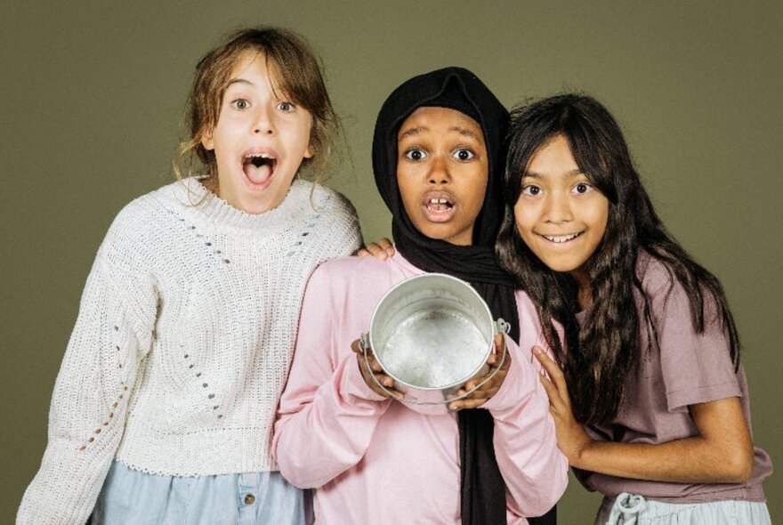 Three kids looking surprised, the middle on holding out an empty tin. 