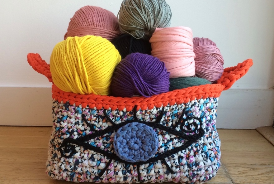 Balls of coloured yarn in a knitted soft basket.