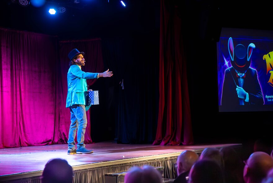 The Great Armando, a children's magician performing on stage in front of a seated audience.