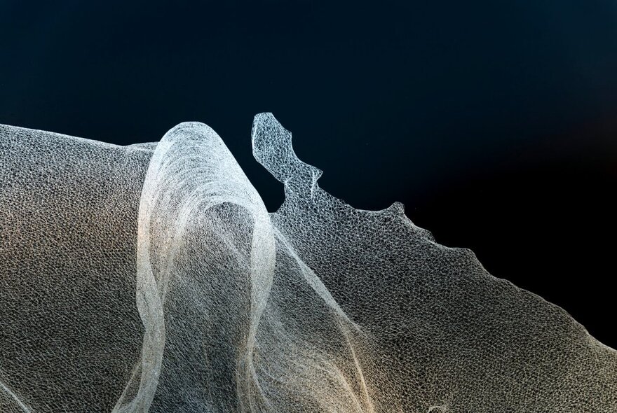 A fine transparent material flowing against a black background. 