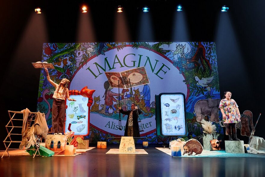 Children's theatrical show staged with props representing animals and nature under floodlights.